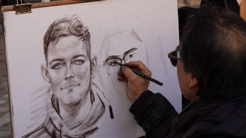 Artiste réalisant un portrait au crayon sur la Place du Tertre à Montmartre, quartier artistique emblématique de Paris.