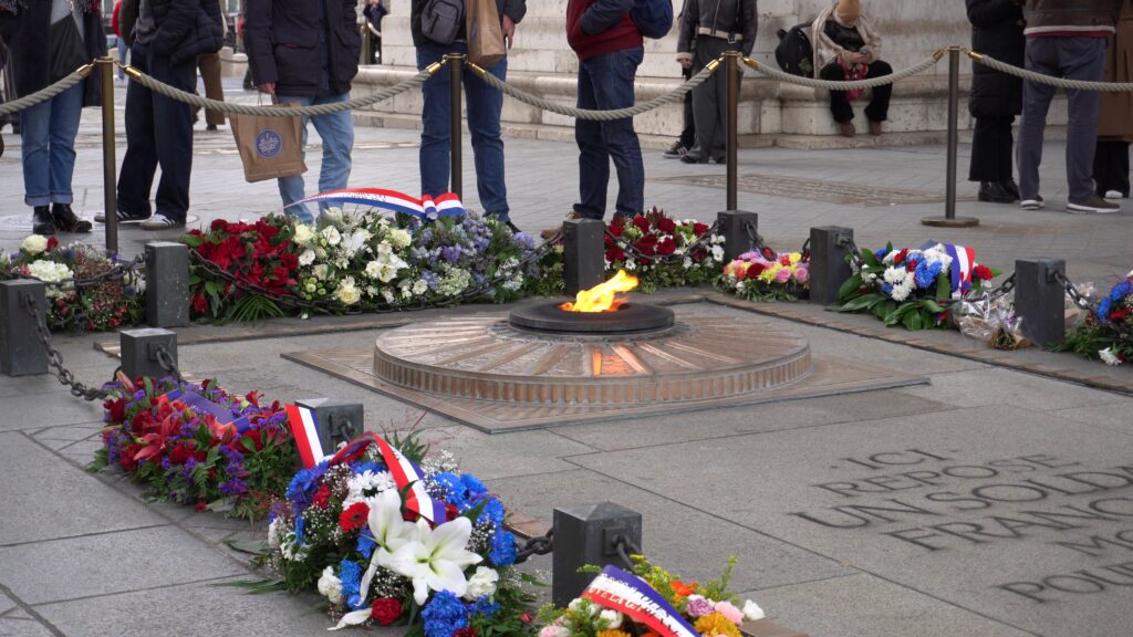 Flamme du Soldat inconnu sous l’Arc de Triomphe à Paris avec gerbes commémoratives.