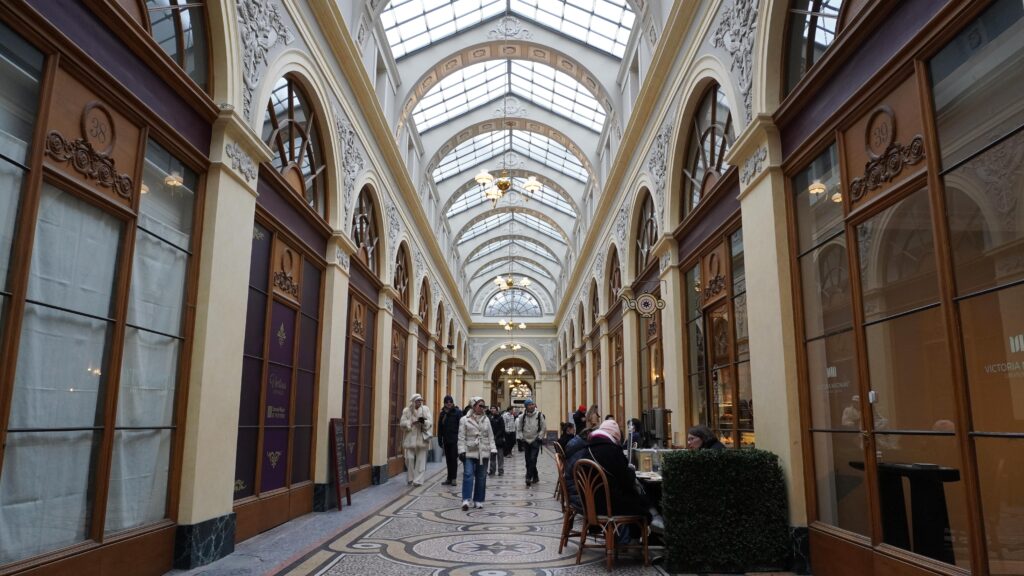 Intérieur de la Galerie Vivienne à Paris avec verrière, mosaïques au sol et boutiques.