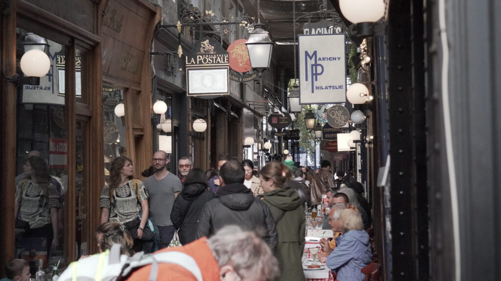 Passage des Panoramas animé à Paris avec visiteurs, boutiques et ambiance de passage couvert.