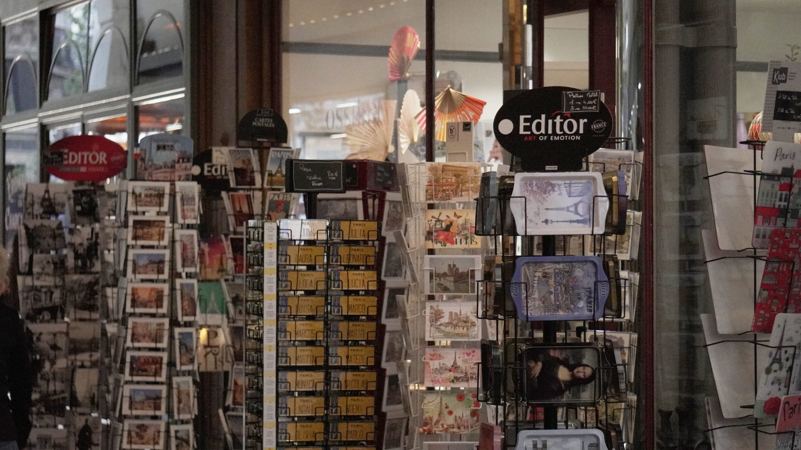 Boutique de cartes postales et souvenirs dans le Passage Jouffroy à Paris, sous la verrière d’un passage couvert historique.