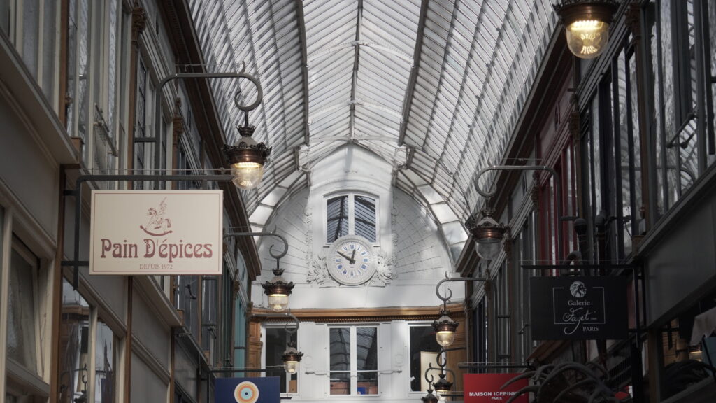 Verrière et horloge du Passage Jouffroy à Paris, avec ses lampes anciennes et ses enseignes historiques.