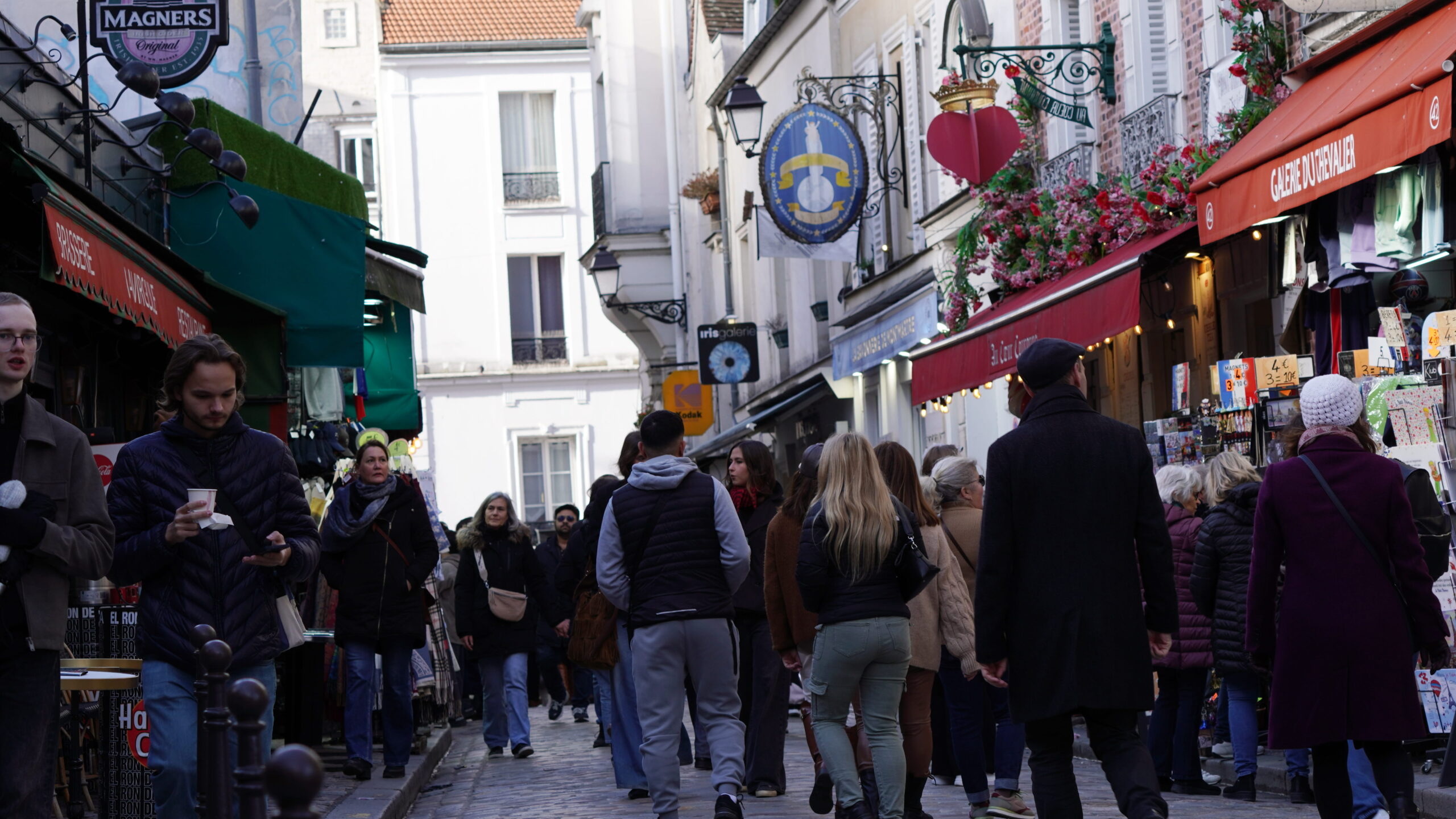 Rue animée de Montmartre à Paris avec touristes, boutiques et ambiance typique du quartier artistique.