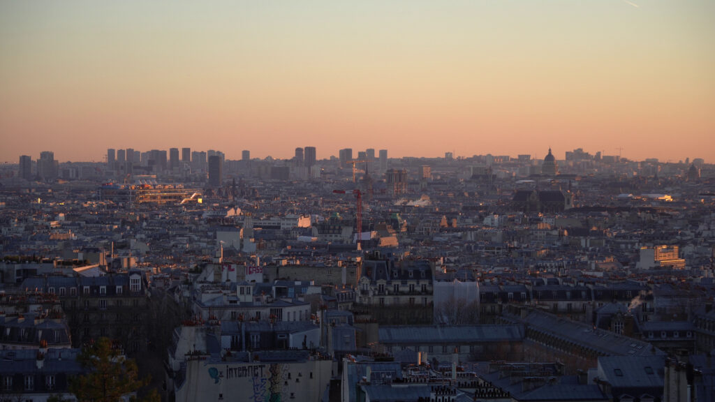 Vue de Paris depuis Montmartre au coucher du soleil avec toits et skyline parisienne.