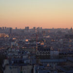 Vue de Paris depuis Montmartre au coucher du soleil avec toits et skyline parisienne.