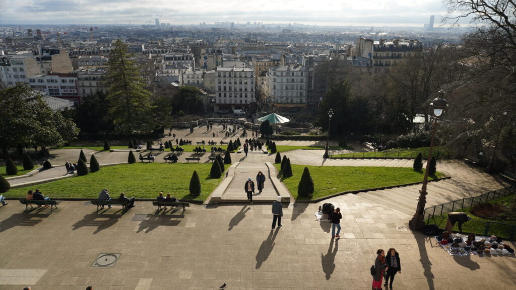 Vue panoramique de Paris depuis Montmartre, avec les jardins du Sacré-Cœur au premier plan.